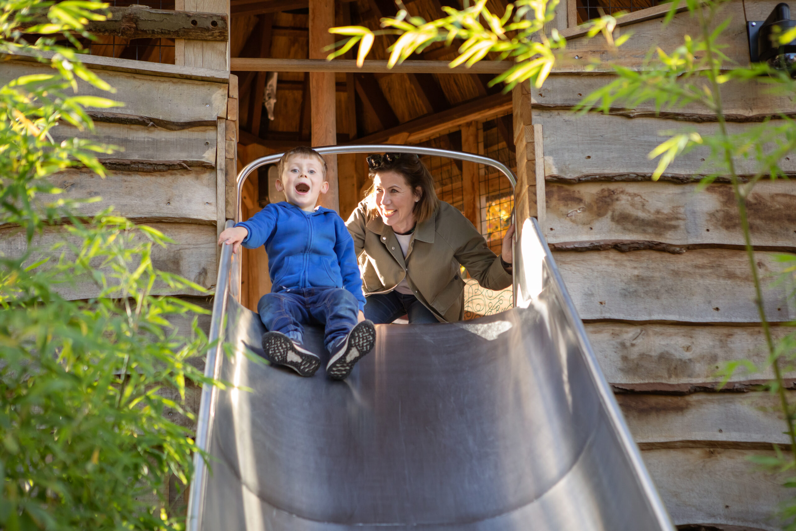 Young child at the top of the slide being encouraged by an adult.