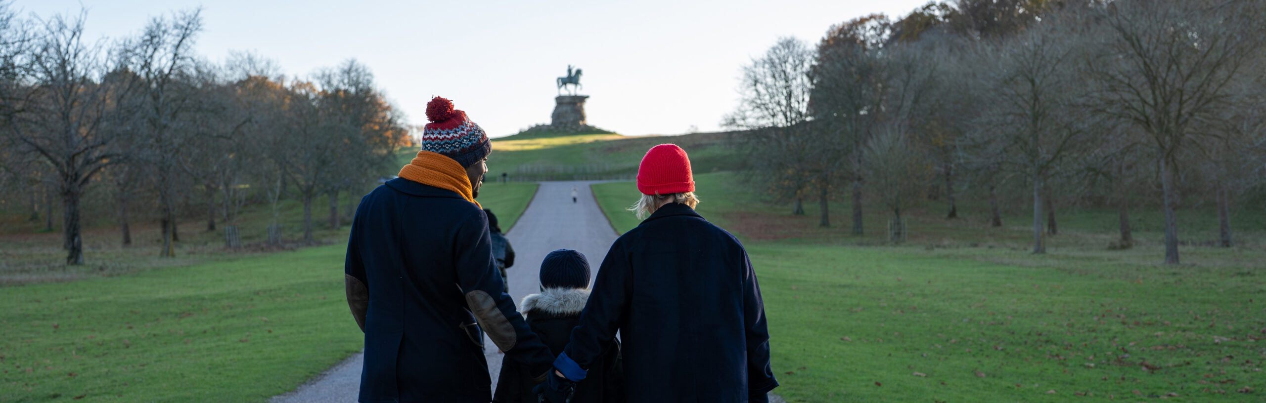 Three people walking up towards the Copper Horse on the Long Walk.