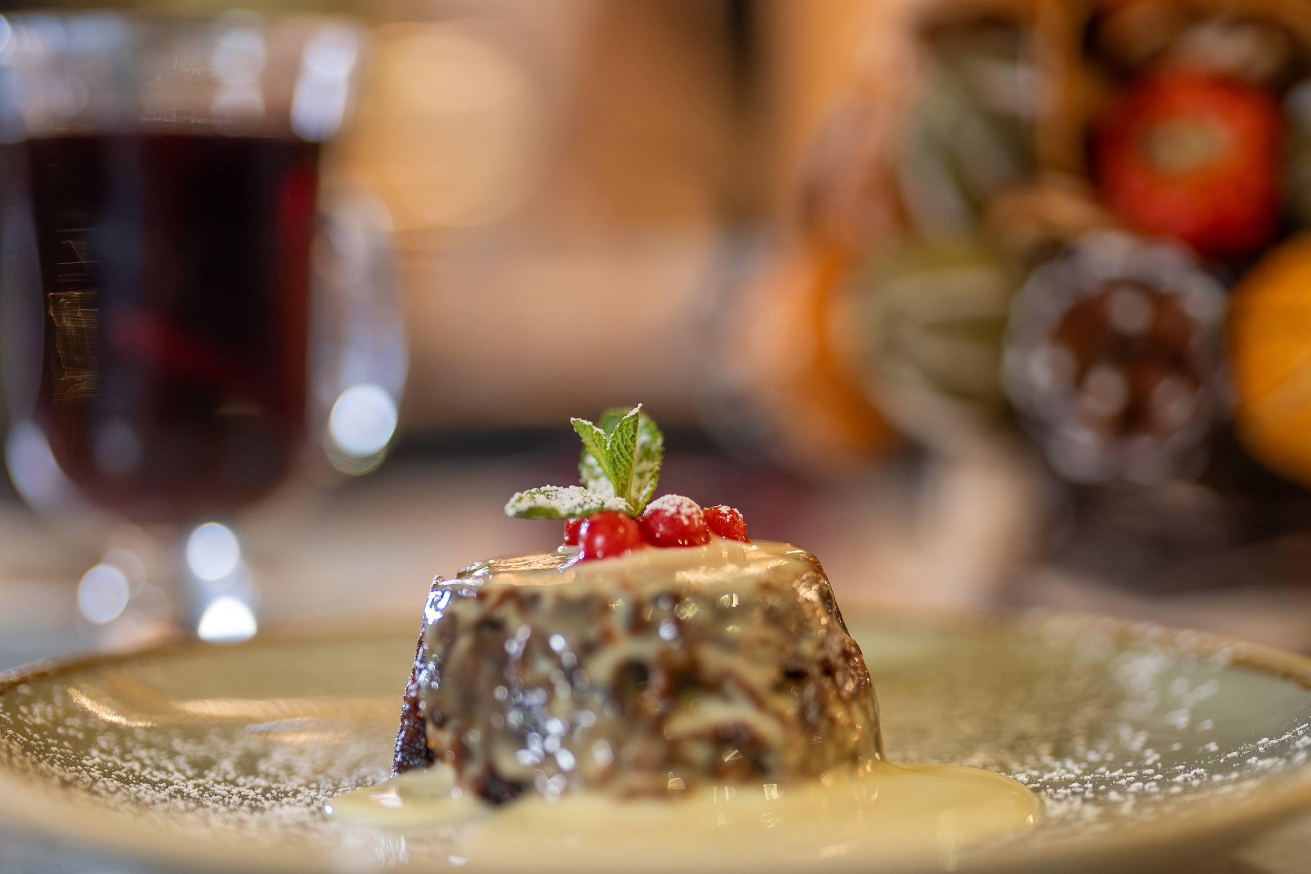 A table laid with a Christmas pudding, mulled wine and Christmas tree decoration.