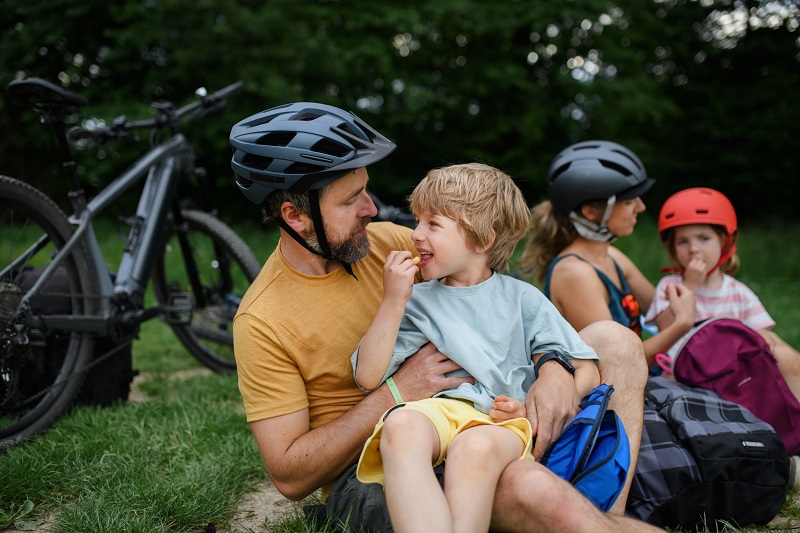 Family taking a rest from cycling, sitting on the grass.